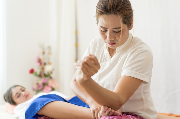 El terapeuta está usando su codo para masajear un pie de mujer