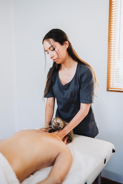 Terapeuta fazendo uma massagem nas costas e pescoço para uma paciente do sexo feminino de rosto para baixo Wellness center spa