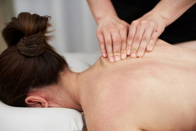Terapeuta feminina massageia uma jovem nas costas e nos ombros. massagem relaxante. massagem terapêutica. medicina alternativa. tratamento de spa.