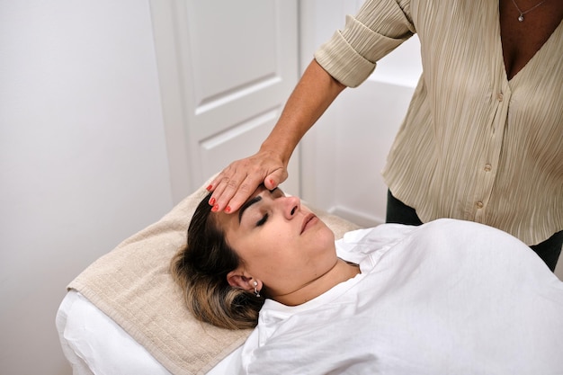 Foto terapeuta feminina trabalhando com as mãos em pontos de energia em um paciente deitado em um estiramento