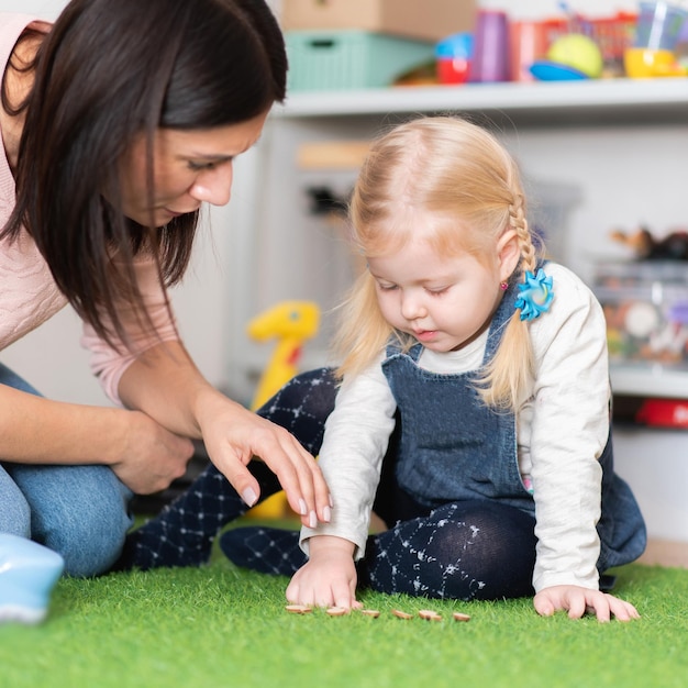 La terapeuta del habla le enseña a una niña la pronunciación correcta y el habla alfabetizada