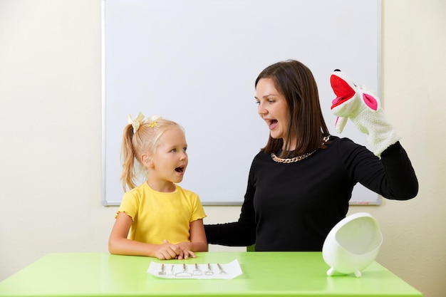 Terapeuta del habla que trabaja con una niña en pronunciación de entrenamiento de oficina