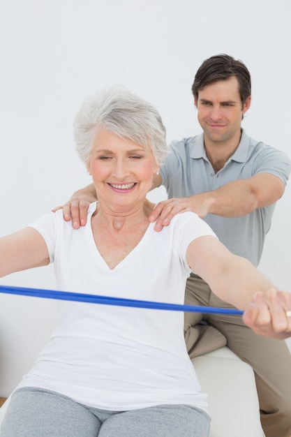 Terapeuta masculino ayudando a mujer senior con ejercicios