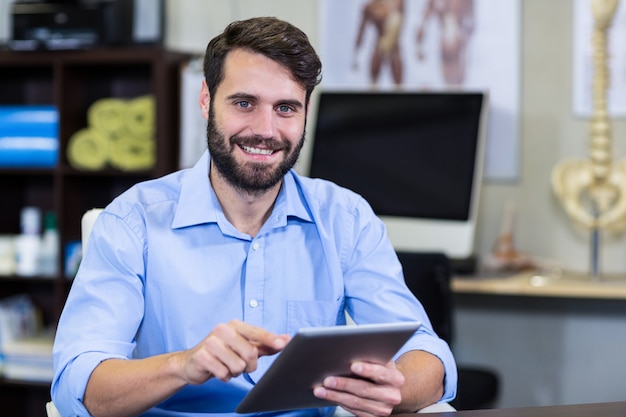 Foto terapeuta masculino con tableta digital en clínica