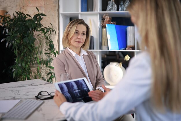 Terapeuta médica de meia idade em consulta com o paciente no escritório.