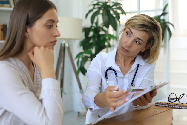 Terapeuta médica feminina de meia idade em consulta com o paciente no consultório.