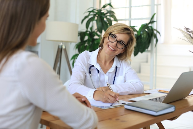 Terapeuta médica feminina de meia idade em consulta com o paciente no consultório.