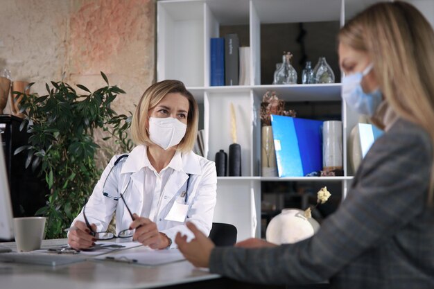 Terapeuta médica de mediana edad en consulta con el paciente en el consultorio.