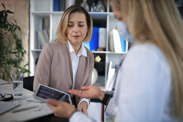 Terapeuta médica de mediana edad en consulta con el paciente en el consultorio.