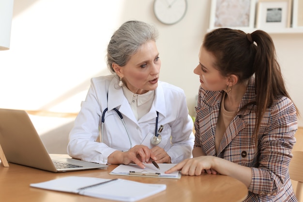 Foto terapeuta médico de mediana edad en consulta con el paciente en la oficina.