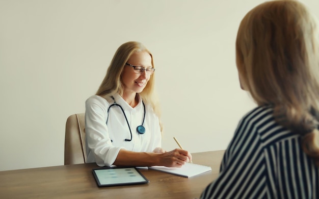 Una terapeuta mujer hablando con una paciente prescribe medicamentos en la oficina de la clínica