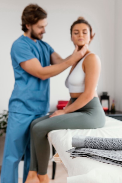 Foto terapeuta osteopata masculino verificando a força do pescoço de paciente do sexo feminino