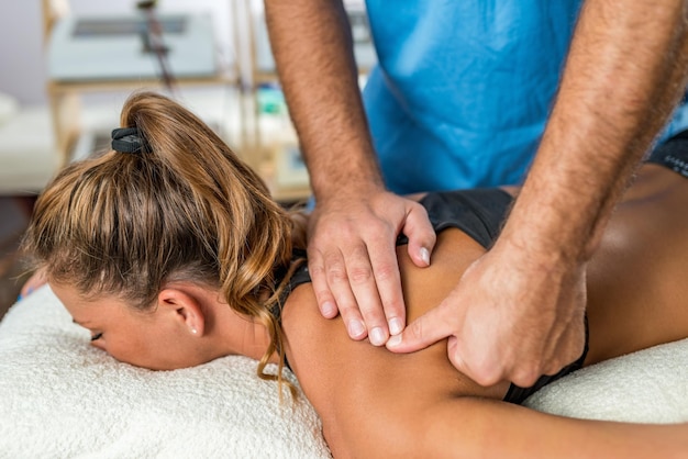 Terapeuta de osteopatía aplicando una fuerte presión a los músculos del hombro