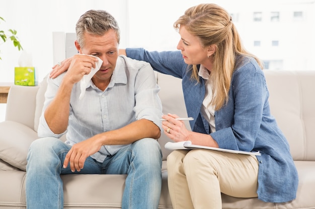 Terapeuta preocupado que conforta o paciente masculino que chora