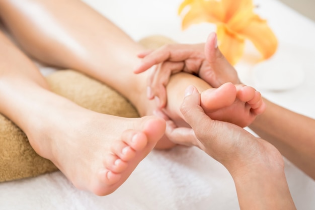 Foto terapeuta profesional dando masaje relajante de reflexología podal a una mujer en spa