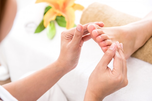 Foto terapeuta profesional dando masaje relajante de reflexología podal a una mujer en spa