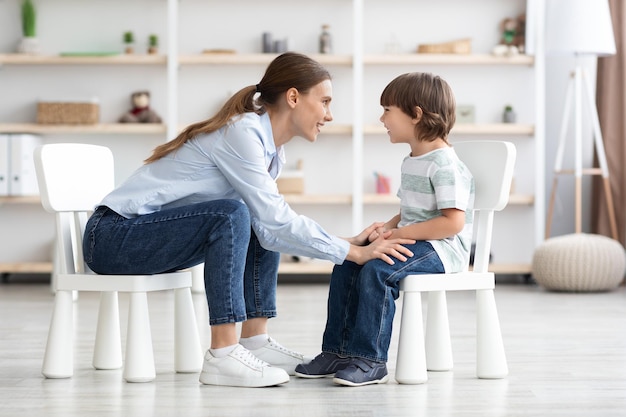 Terapeuta profissional jovem se comunicando com um garotinho feliz falando durante pessoal