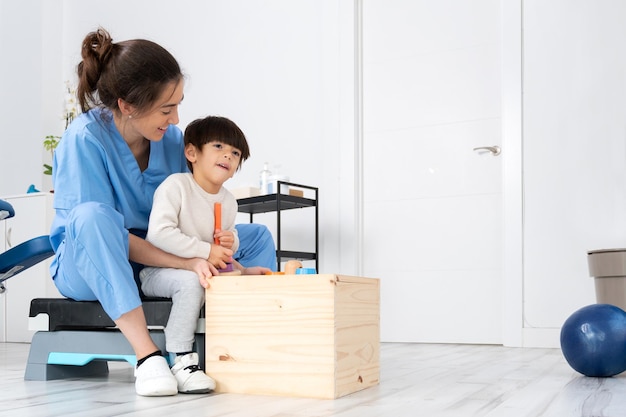 Terapeuta realizando actividades de desarrollo con un niño con parálisis cerebral en rehabilitación ...