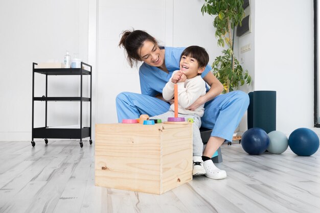 Terapeuta realizando actividades de desarrollo con un niño con parálisis cerebral en rehabilitación ...