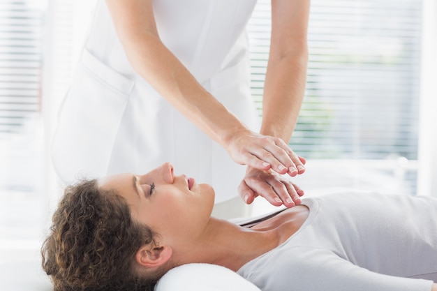 Terapeuta realizando Reiki sobre mujer