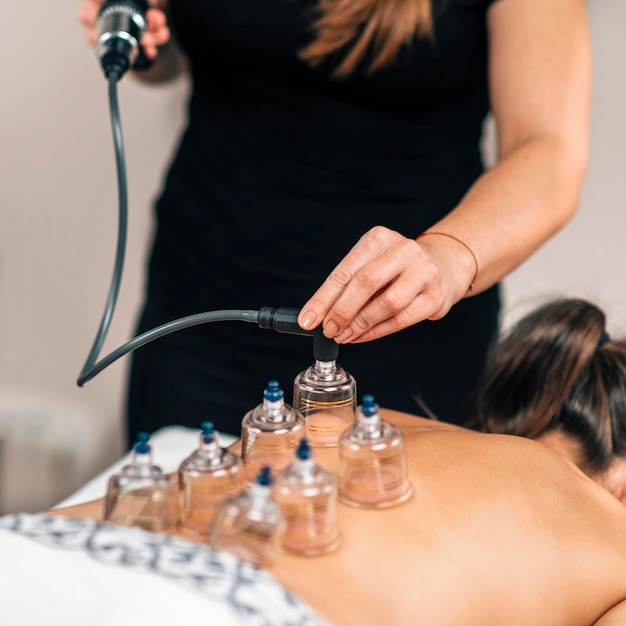 Foto terapeuta de vacío colocando copas de vidrio transparente en la espalda de la mujer