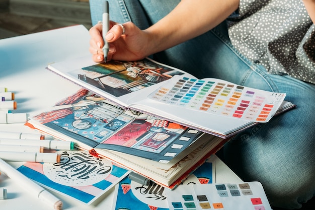 Terapia artística. Pintor sentado en el lugar de trabajo y dibujo con paleta en cuaderno de bocetos.