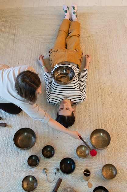 Terapia do tibete com taças cantantes para menina receber massagem sonora com pratos de bronze em casa para relaxar