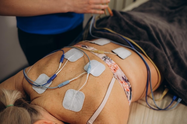 Foto terapia física de la parte baja de la espalda con pastillas de electrodos tens electrodos de estimulación eléctrica transcutánea del nervio electrodos en la parte baja de la espalda del paciente foto de alta calidad