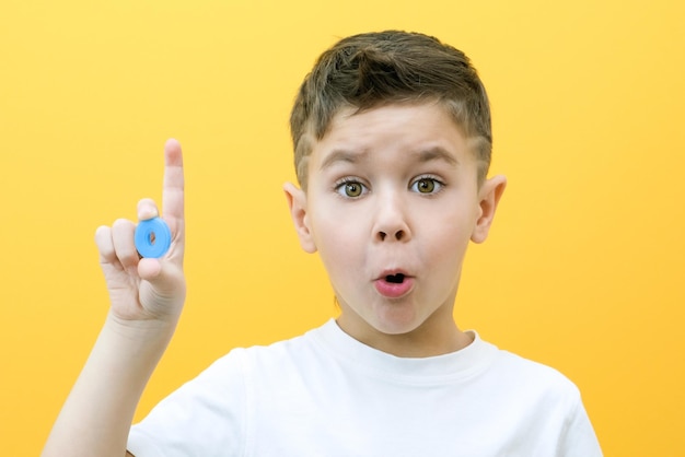 Terapia del lenguaje. El niño pequeño dice la letra O. Clases con un logopeda. niño sobre fondo amarillo aislado