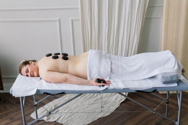 Foto terapia de masaje con piedras calientes para mujer gorda, maestro masculino