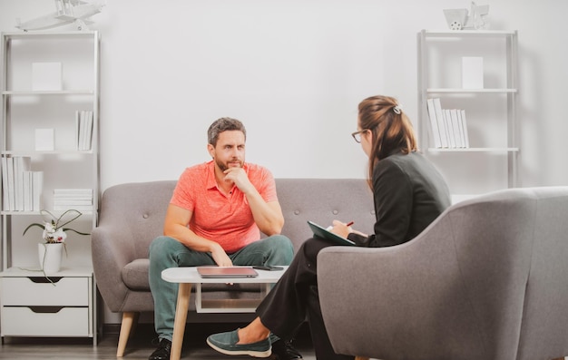 Terapia de problemas de un hombre de mediana edad Un hombre guapo está sentado en el sofá y hablando con el psicólogo El paciente de Psicología habla sobre su salud mental durante la consulta psicológica