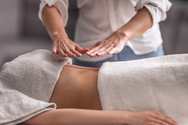 Foto terapia de reiki en una paciente con el terapeuta sosteniendo ambas manos sobre el pecho y el abdomen de una clienta.