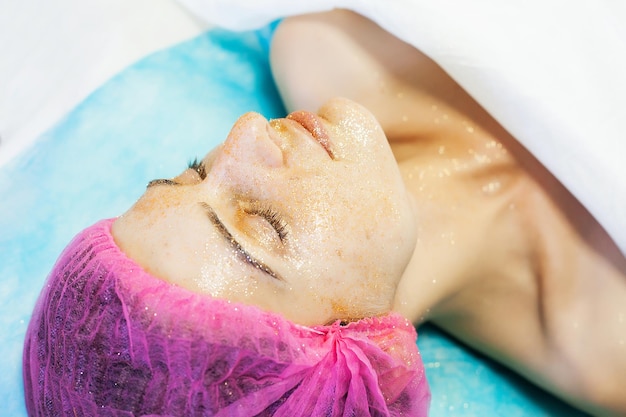 Terapia de spa para mujeres jóvenes con máscara facial en el salón de belleza