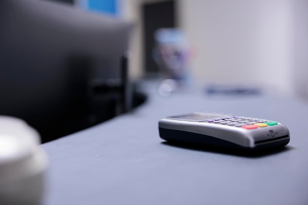 Terminal bancário na mesa na área do caixa da instituição médica. Gadget tecnológico para receber pagamentos de pacientes no balcão da clínica médica. Ferramenta de cobrança de pagamento com cartão bancário no hospital.