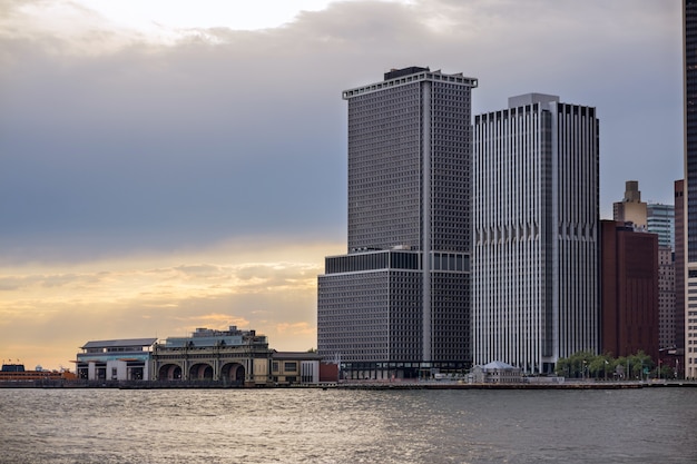 Terminal de balsas de Staten Island no horizonte do distrito financeiro de Lower Manhattan, cidade de Nova York com arranha-céus contemporâneos, prédios de escritórios, pôr do sol em barco de transporte público ancorado