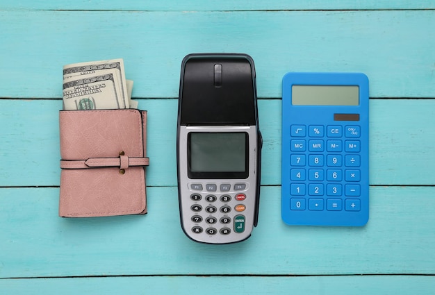 Terminal de pagamento com calculadora de fita de dinheiro e bolsa na mesa de madeira azul Vista superior