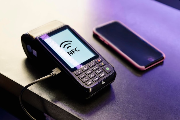 Foto terminal pos máquina de pagamento com celular em fundo escuro pagamento sem contato com tecnologia nfc pagamento aprovado