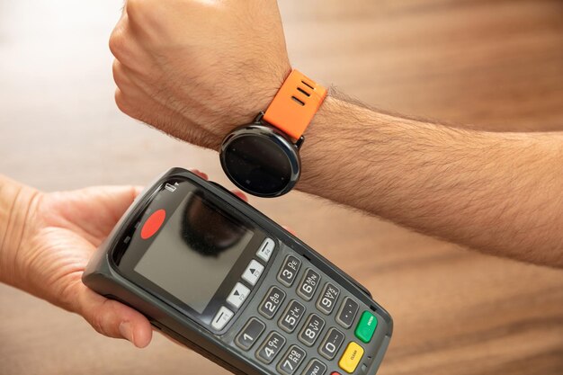 Terminal pos para pago con reloj inteligente tecnología nfc cajero y manos  del cliente