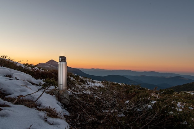 Termo de viaje para bebidas calientes Termo en la cima de la montaña Termo piedras de nieve y montañas Con termo afuera Vista frontal