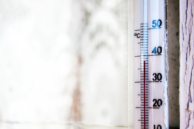 Un termómetro Celsius en un marco de ventana de madera de una casa de campo muestra temperaturas de hasta 38 grados en el exterior