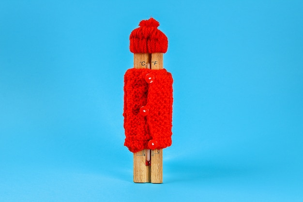 Termômetro de madeira, vestindo um chapéu vermelho e blusa azul