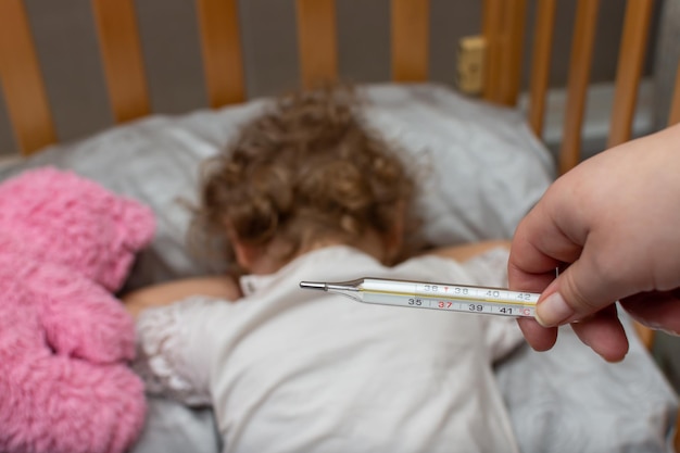 Termômetro de mercúrio e criança doente na cama
