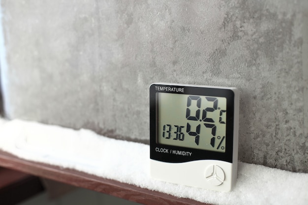 Foto termómetro digital en una ventana con nieve. termómetro e higrómetro electrónicos para control de temperatura y humedad
