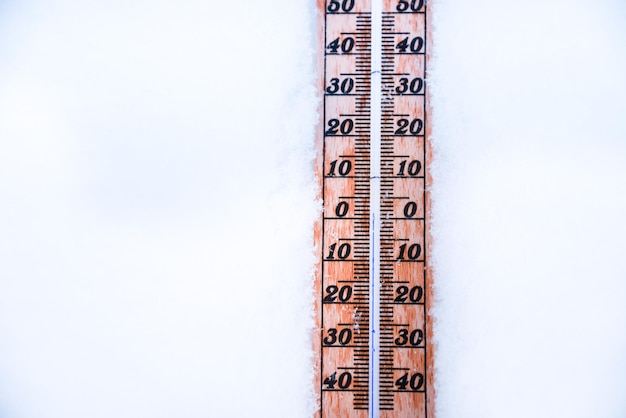 Termômetro na neve com baixas temperaturas em celsius ou fahrenheit no inverno.