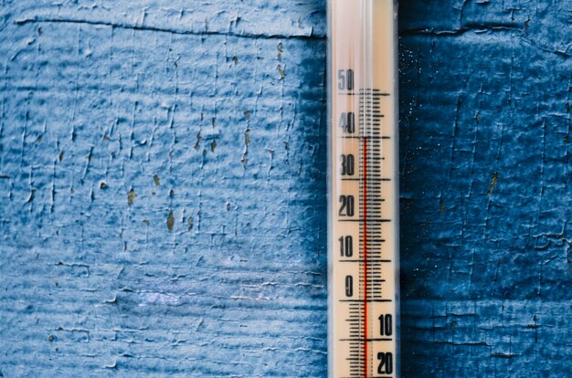 Termómetro en la pared de madera vieja, concepto de clima caliente.