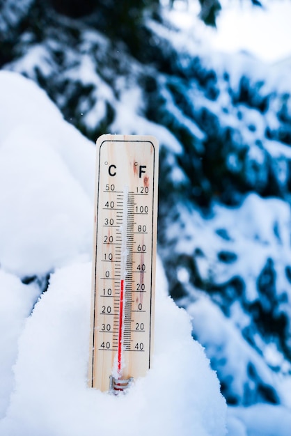 Termómetro sobre nieve con bajas temperaturas en celsius o fahrenheit en invierno.