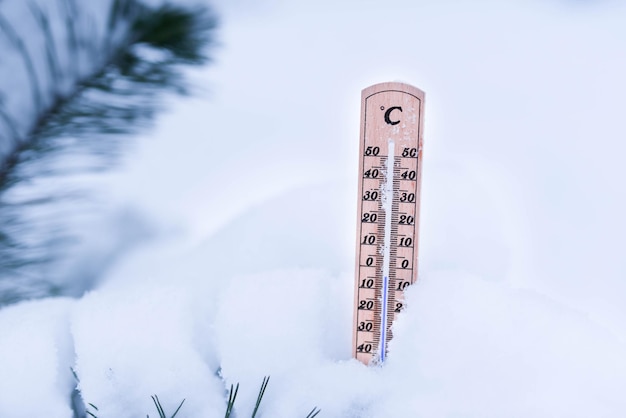 Termómetro sobre nieve con bajas temperaturas en celsius o fahrenheit en invierno.