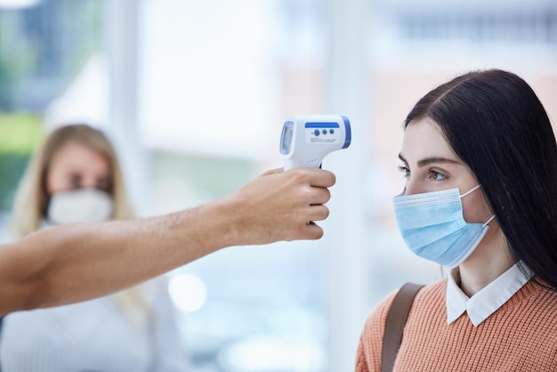 Termómetro de viaje y escaneo de covid en el aeropuerto con una mujer y cumplimiento de seguridad y verificación de seguridad Corona de salud y trabajador verificando los resultados digitales de la dama antes de viajar al control fronterizo