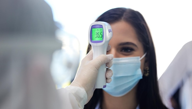 Termómetro de virus y temperatura de la mujer en la oficina con exámenes de salud o consulta con el médico para el examen Pruebas de seguridad y empleados con máscara para el riesgo de pandemia de COVID o cumplimiento de la protección