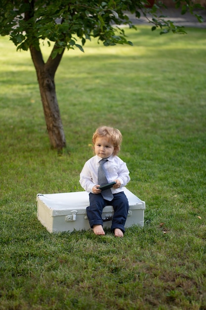 Terno de bebê e gravata em criança de grama verde se divertindo no piquenique em família no jardim de verão bonito b